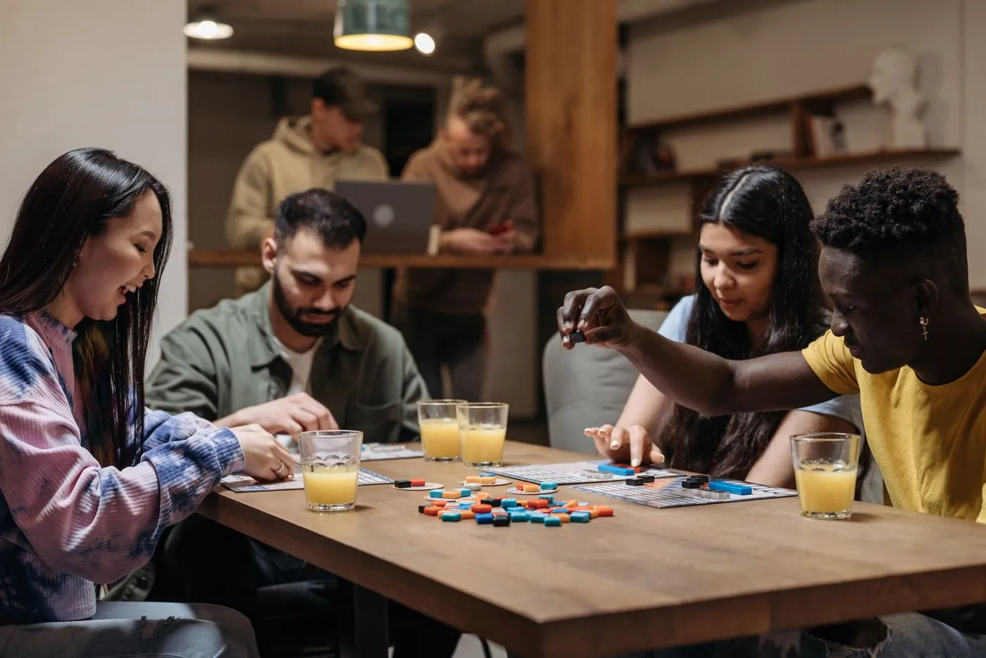 Gruppo di amici adulti che gioca a un gioco di società attorno a un tavolo durante una serata in compagnia